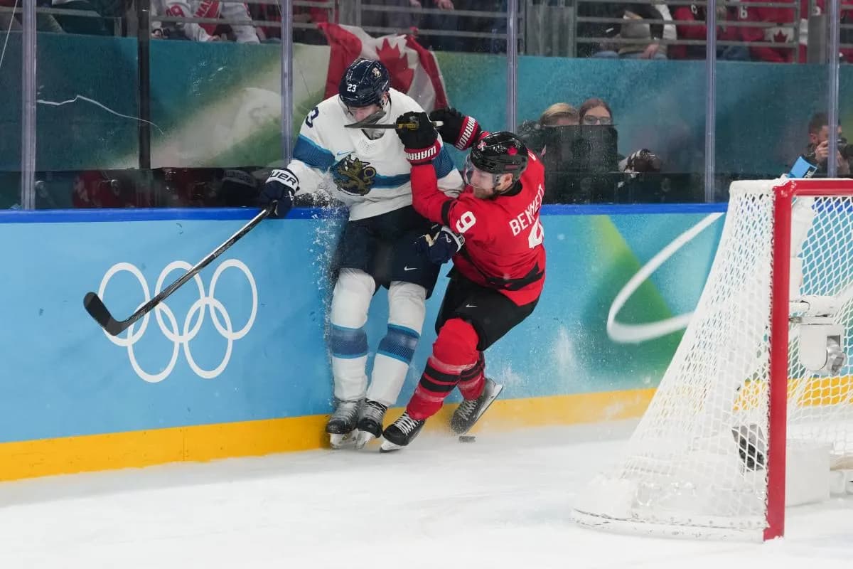 Sam Bennett (9) of Canada checks Esa Lindell (23) of Finland into the boards during the second period in a men's ice hockey semifinal during the Milano Cortina 2026 Olympic Winter Games at Milano Santagiulia Ice Hockey Arena.