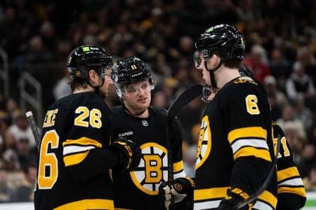 Boston Bruins defenseman Andrew Peeke (26), center Casey Mittelstadt (11), and defenseman Mason Lohrei (6) talk during a stop in play during the second period of the game against the Detroit Red Wings at TD Garden.