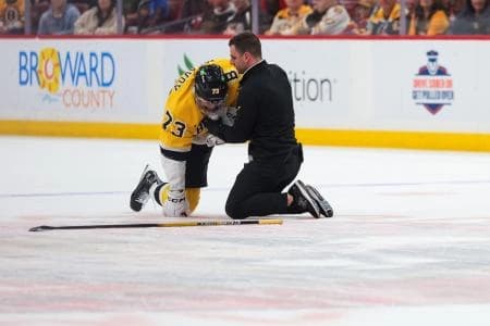 Boston Bruins defenseman Charlie McAvoy (73) is looked at by a trainer after an apparent injury against the Florida Panthers during the first period at Amerant Bank Arena.