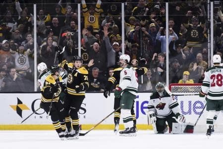 Boston Bruins defenseman Charlie McAvoy (73) reacts with center Matthew Poitras (51) after scoring a goal during the second period against the Minnesota Wild at TD Garden.