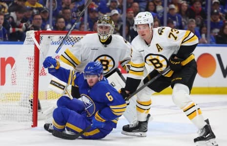 Boston Bruins defenseman Charlie McAvoy (73) knocks down Buffalo Sabres left wing Zach Benson (6) in front of the net as Boston Bruins goaltender Jeremy Swayman (1) watches the puck during the second period in game one of the first round of the 2026 Stanley Cup Playoffs at KeyBank Center.