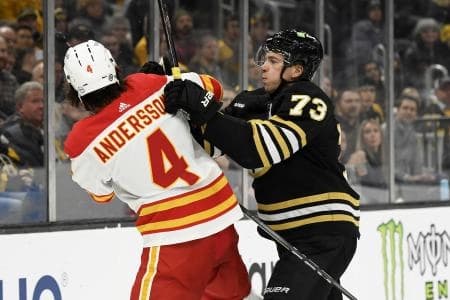 Boston Bruins defenseman Charlie McAvoy (73) shoves Calgary Flames defenseman Rasmus Andersson (4) during the third period at TD Garden.
