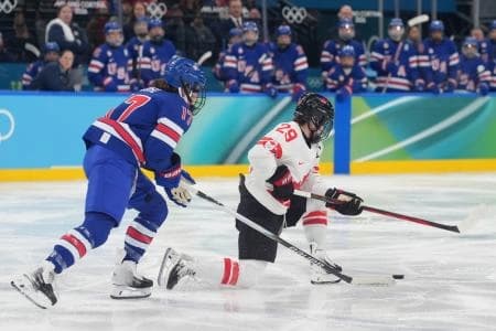 Marie-Philip Poulin (29) of Canada looks to control the puck as Britta Curl (17) of the United States defends in the women's ice hockey gold medal game during the Milano Cortina 2026 Olympic Winter Games at Milano Santagiulia Ice Hockey Arena.