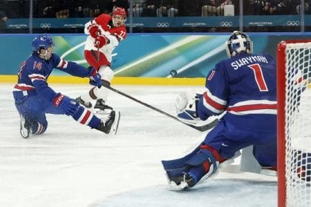 Markus Lauridsen of Denmark in action with Brock Faber of United States and Jeremy Swayman of United States as he shoots at goal in men's ice hockey group C play during the Milano Cortina 2026 Olympic Winter Games at Milano Santagiulia Ice Hockey Arena.