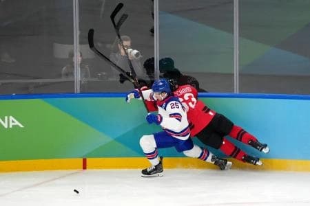 Charlie McAvoy of the United States battles for the puck against Brad Marchand of Canada during the men's ice hockey gold medal game during the Milano Cortina 2026 Olympic Winter Games at Milano Santagiulia Ice Hockey Arena.