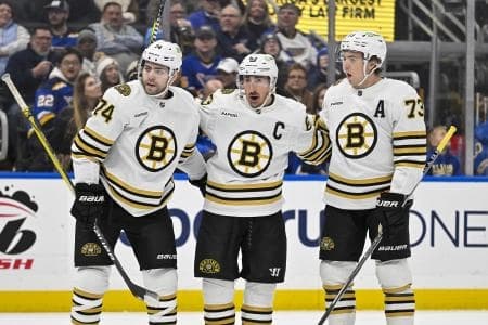 Boston Bruins left wing Brad Marchand (63) is congratulated by left wing Jake DeBrusk (74) and defenseman Charlie McAvoy (73) after scoring against the St. Louis Blues during the first period at Enterprise Center.
