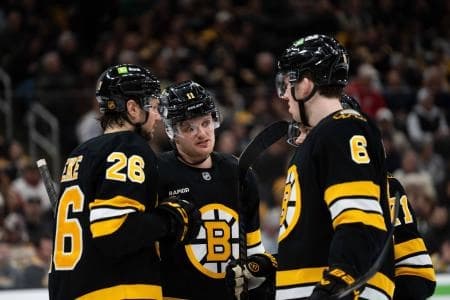 Boston Bruins defenseman Andrew Peeke (26), center Casey Mittelstadt (11), and defenseman Mason Lohrei (6) talk during a stop in play during the second period of the game against the Detroit Red Wings at TD Garden.