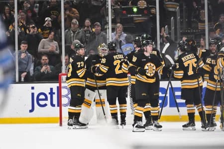 Boston Bruins goaltender Jeremy Swayman (1) celebrates defeating the Winnipeg Jets with defenseman Andrew Peeke (26) and defenseman Charlie McAvoy (73) at TD Garden.