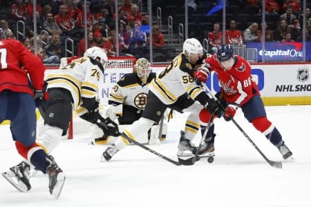Washington Capitals left wing Andrew Mangiapane (88) and Boston Bruins defenseman Billy Sweezey (58) battle for the puck in front of Bruins goaltender Brandon Bussi (30) in the first period at Capital One Arena.