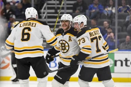 Boston Bruins right wing David Pastrnak (88) celebrates with defenseman Charlie McAvoy (73) and defenseman Mason Lohrei (6) after scoring the game winning goal against the St. Louis Blues during the third period at Enterprise Center.