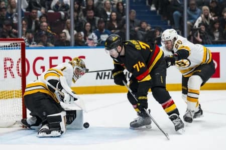 Boston Bruins defenseman Andrew Peeke (26) checks Vancouver Canucks forward Jake DeBrusk (74) as Boston Bruins goalie Jeremy Swayman (1) makes a save in the second period at Rogers Arena.