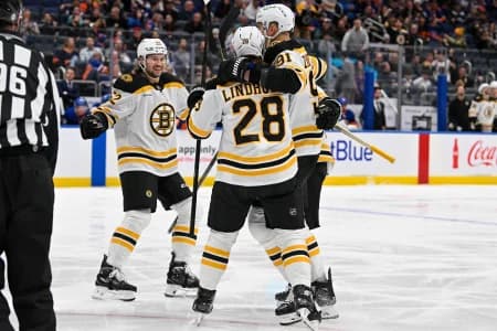 Boston Bruins left wing Brad Marchand (63) celebrates his goal against the New York Islanders with Boston Bruins center Elias Lindholm (28) Boston Bruins defenseman Andrew Peeke (52) and Boston Bruins defenseman Nikita Zadorov (91) during the first period at UBS Arena.